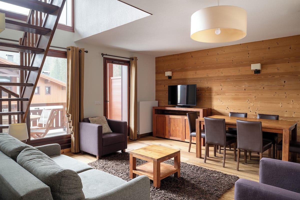 A modern living room with a sofa, coffee table, and dining area.
