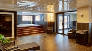 A modern spa area with a hot tub, seating, and a staircase leading to an upper level. - Dormio Resort Les Portes du Mont Blanc (Vallorcine)