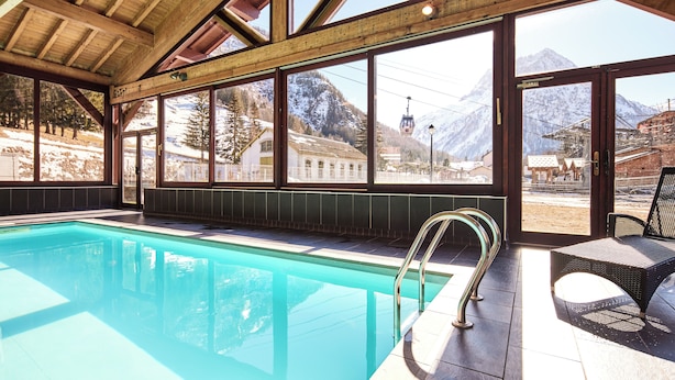 A swimming pool with a view of mountains and a ski lift. - Dormio Resort Les Portes du Mont Blanc (Vallorcine)