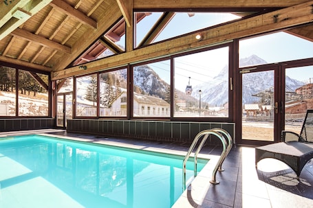 A swimming pool with a view of mountains and a ski lift.