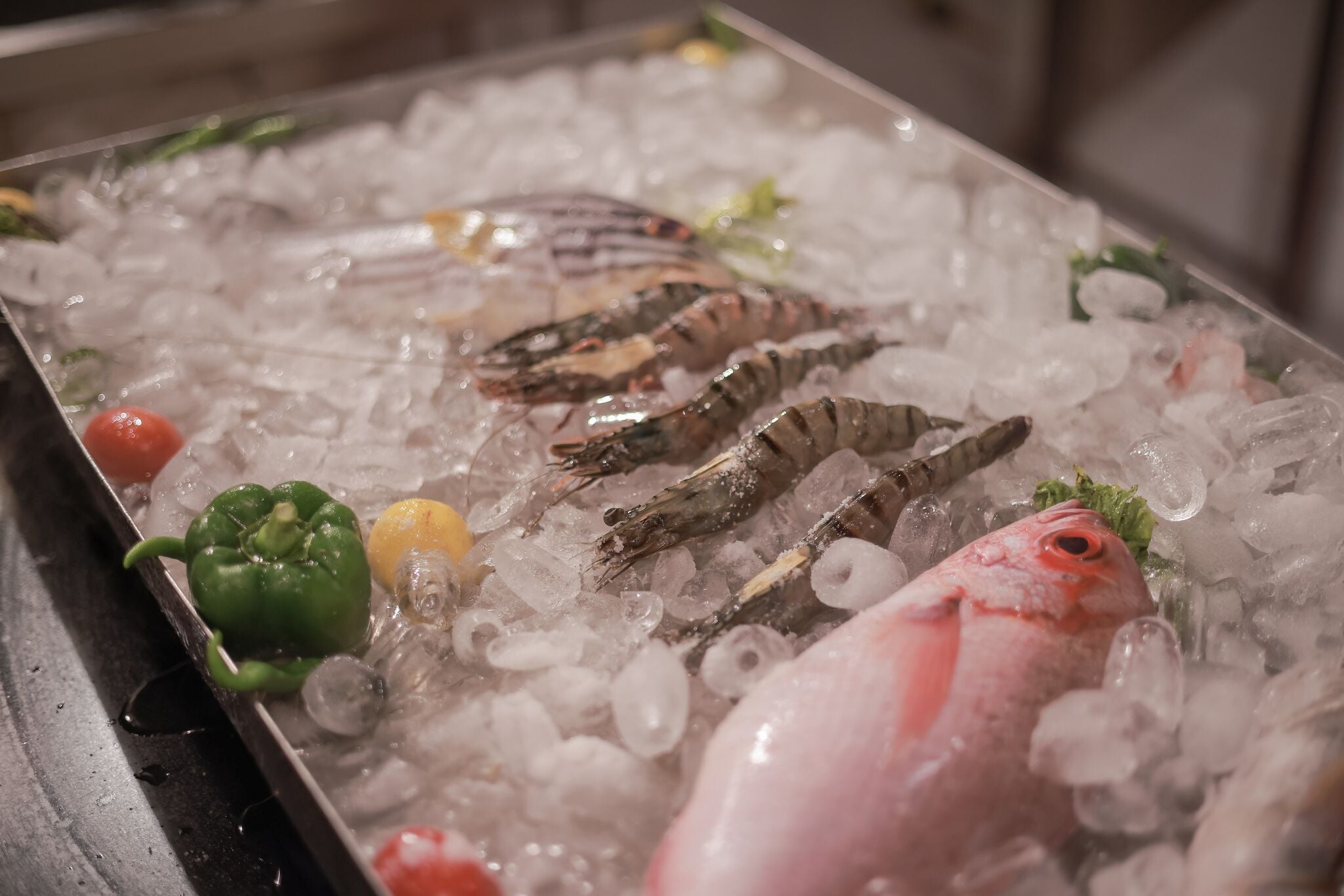 A seafood display with ice, shrimp, and a fish on a tray.