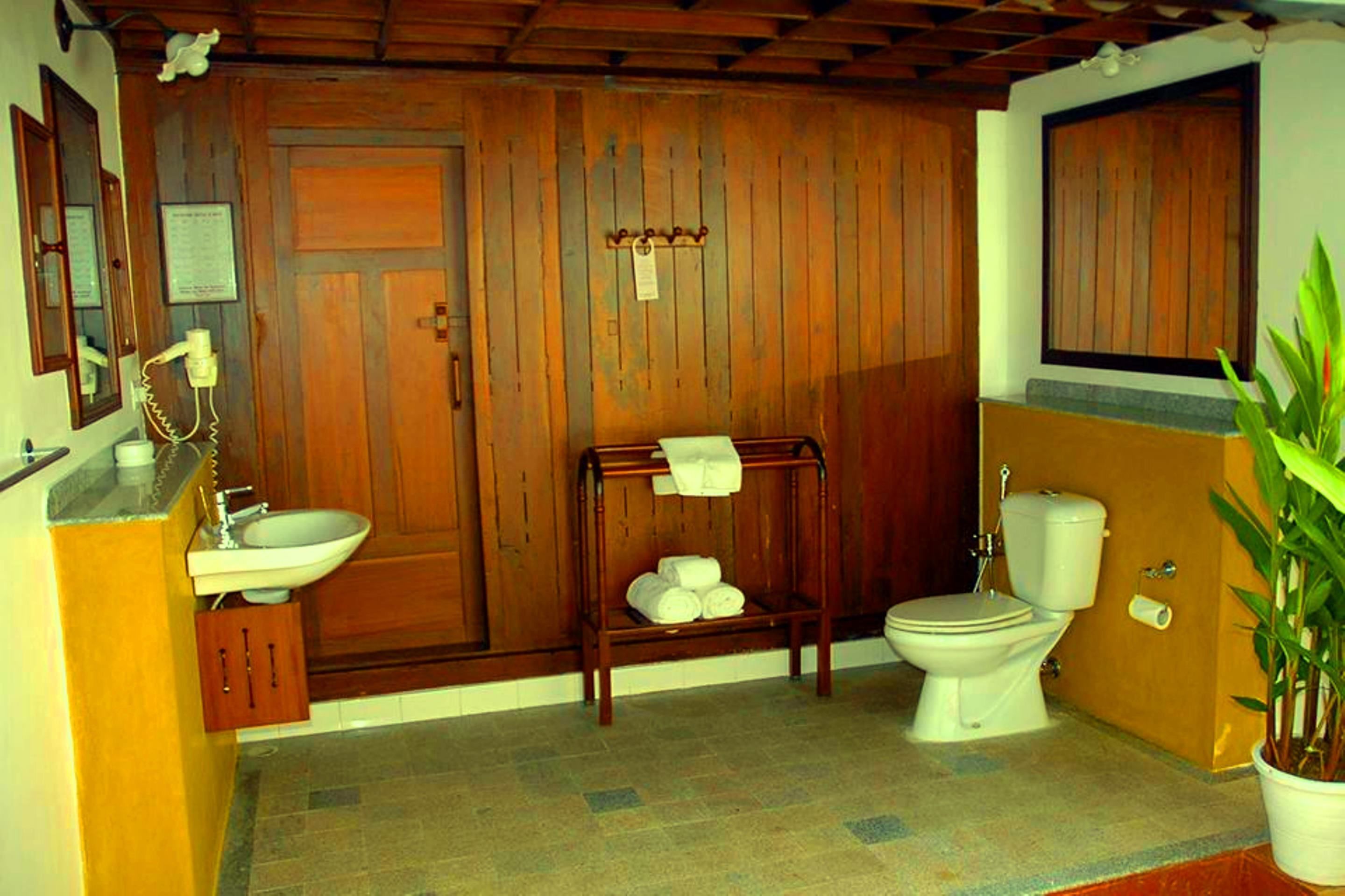 A bathroom with wooden walls, a sink, a toilet, and a towel rack.