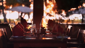 Una mesa de restaurante dispuesta con servilletas rojas, una jarra de vidrio y una vela.