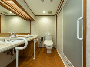 A bathroom with a wooden floor, a white sink with a handheld showerhead, a toilet, and a handrail. - Gion Shinmonso (Kyoto)