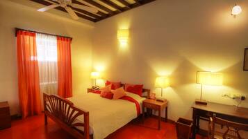 A hotel room with a bed, bedside tables, a desk, and a chair.