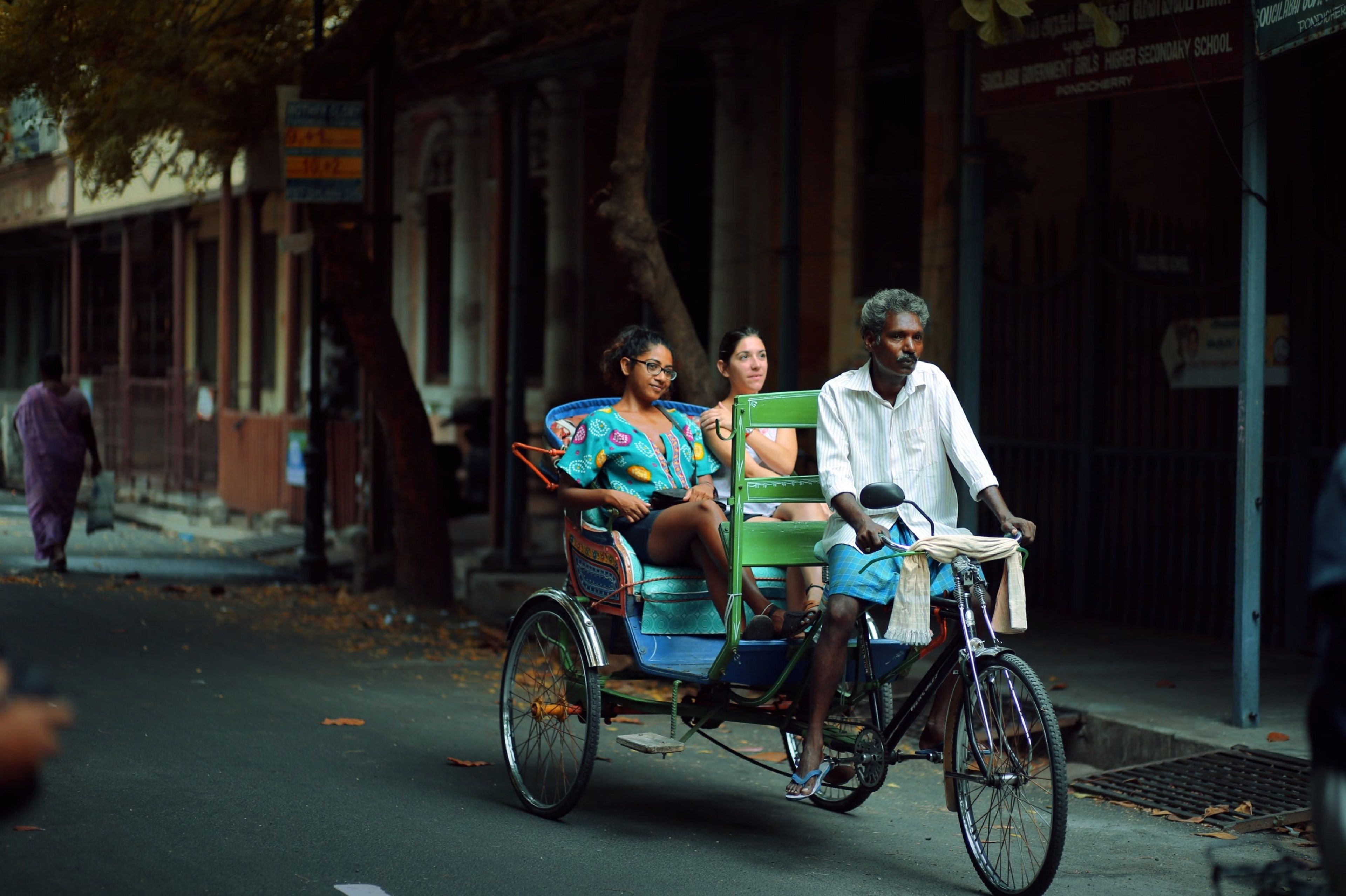 Un rickshaw con tres pasajeros en una calle.