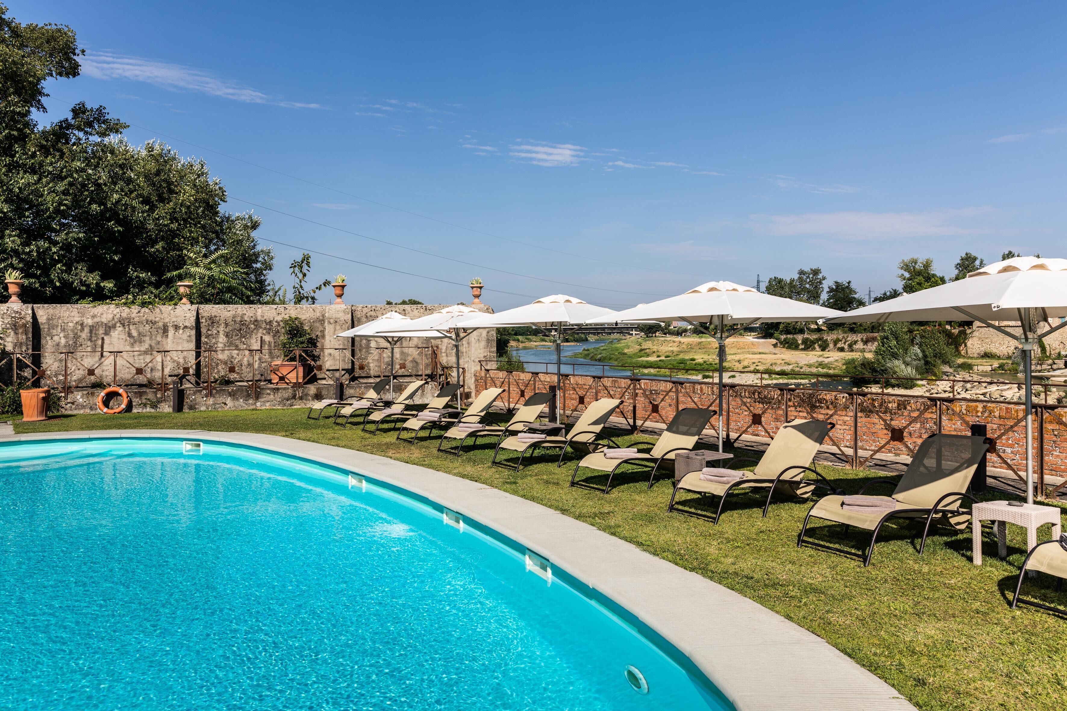 A swimming pool with lounge chairs and umbrellas.