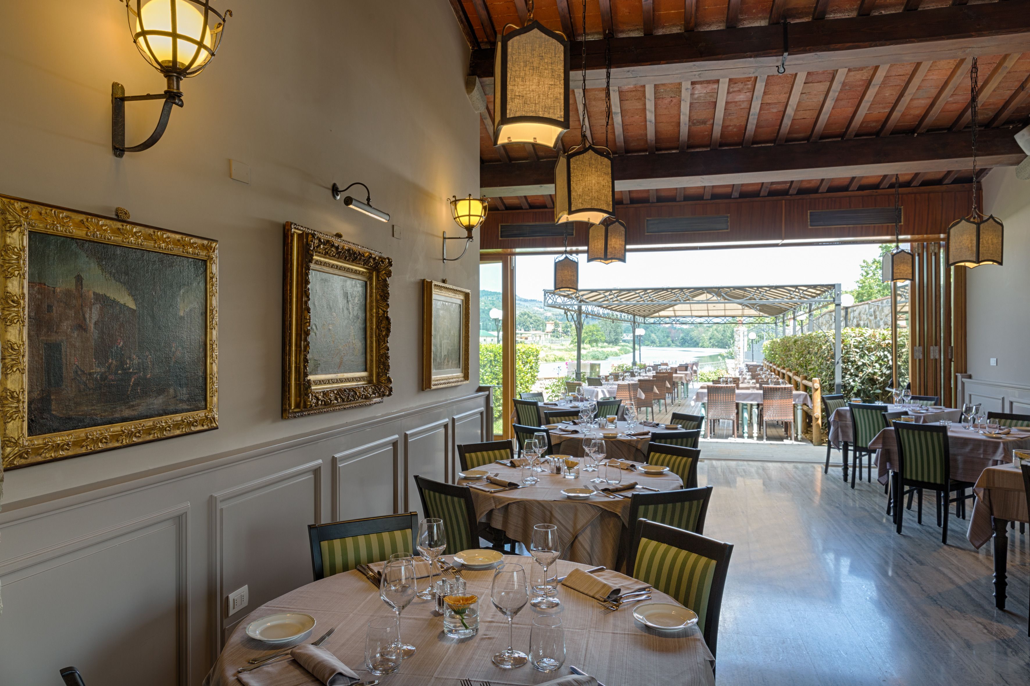 En restaurant med borde dækket til spisning, billeder på væggene og udsigt til det fri.
