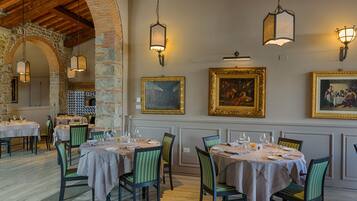 A restaurant with tables set for dining, framed artwork on the walls, and hanging light fixtures.