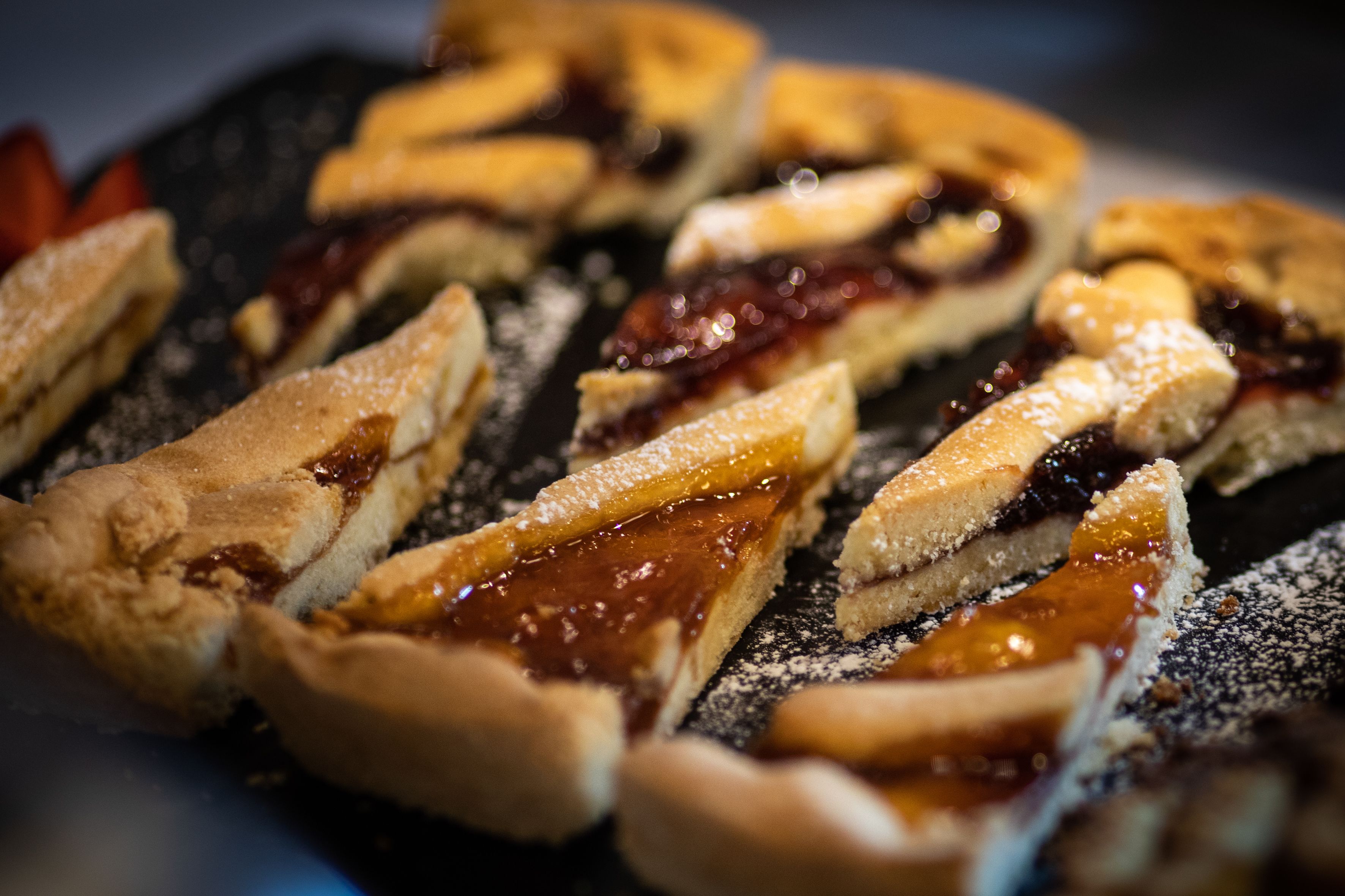 A dessert tray with various pastries, including a layered cake and a fruit-topped pastry, dusted with powdered sugar.