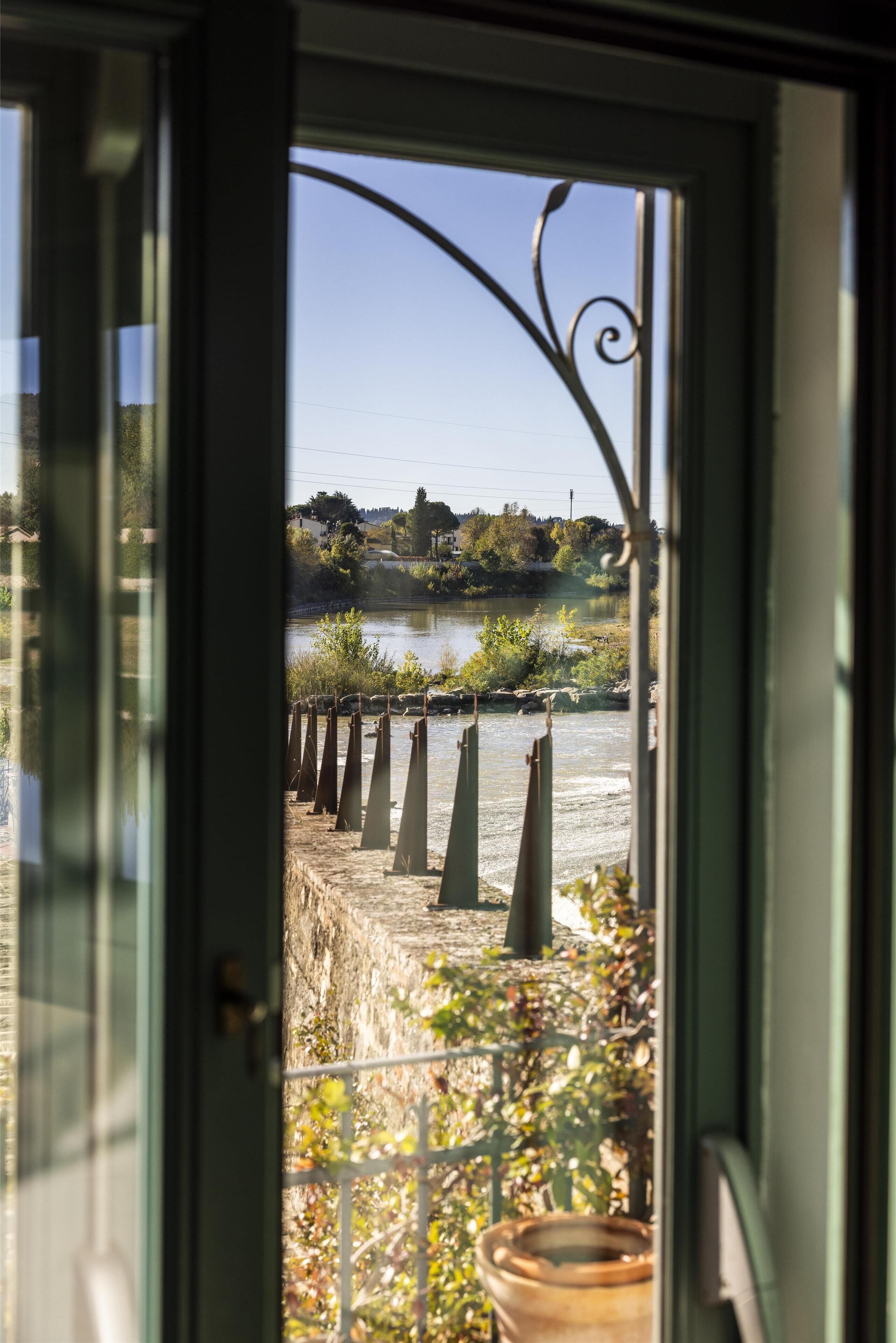 A view through a glass door with a metal railing, a body of water, and a distant landscape.