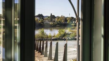 A view through a glass door with a metal railing, a body of water, and a distant landscape.