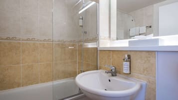 Un baño con ducha de vidrio, lavamanos blanco y bañera.