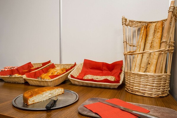 A table with a cake, a knife, and baskets of bread. - Comfort Hotel Etampes (Etampes)