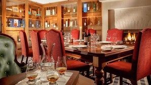 A dining area with a wooden table set for a meal, surrounded by red upholstered chairs. - Greywalls Hotel and Chez Roux (Gullane)