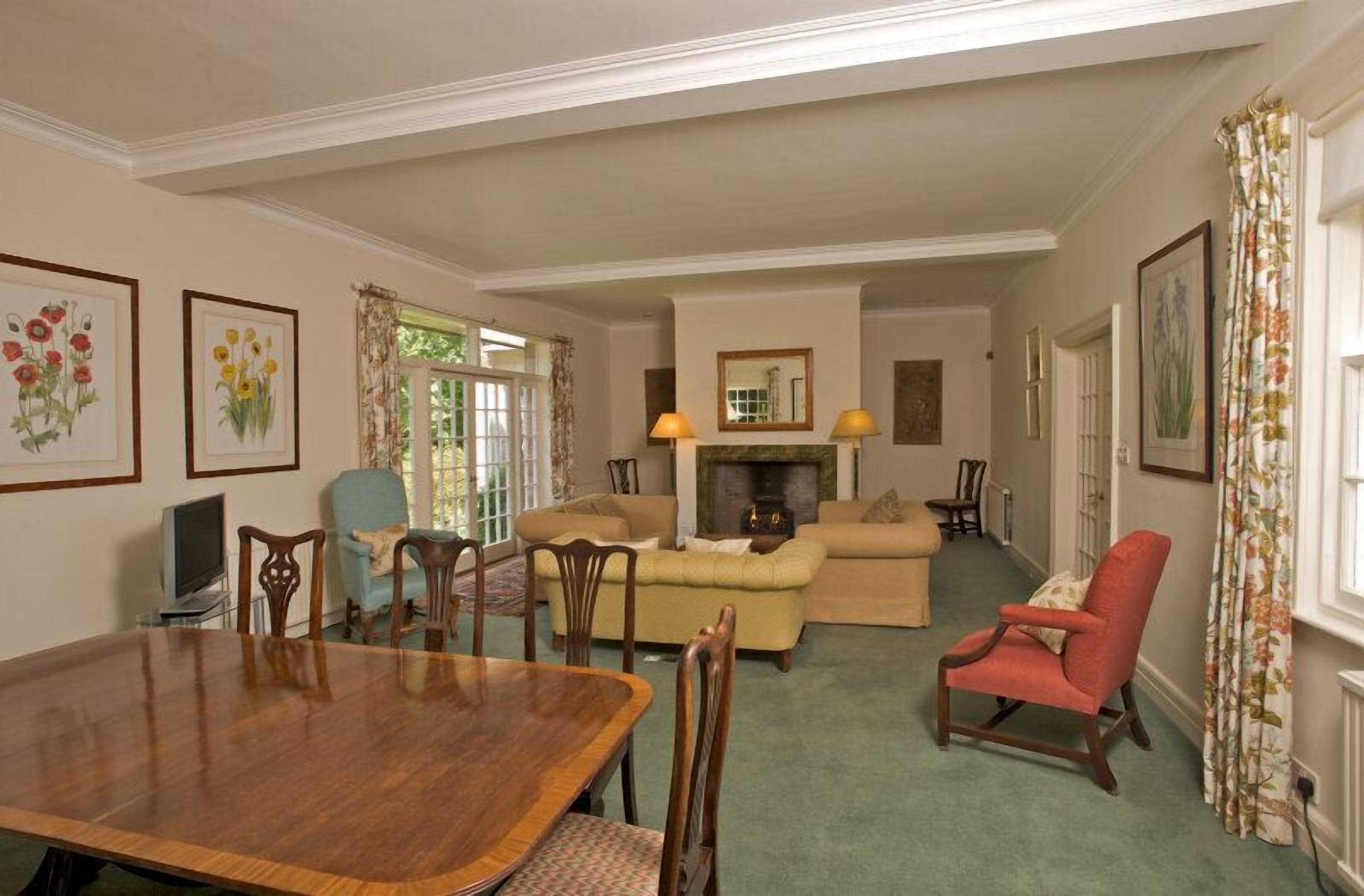 A dining area with a wooden table and chairs, a sofa, and a fireplace.