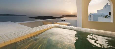 A hot tub with a view of the sea and a sunset.
