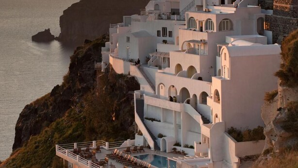 A coastal building with a pool and multiple balconies overlooking the sea. - Tzekos Villas (Santorini)