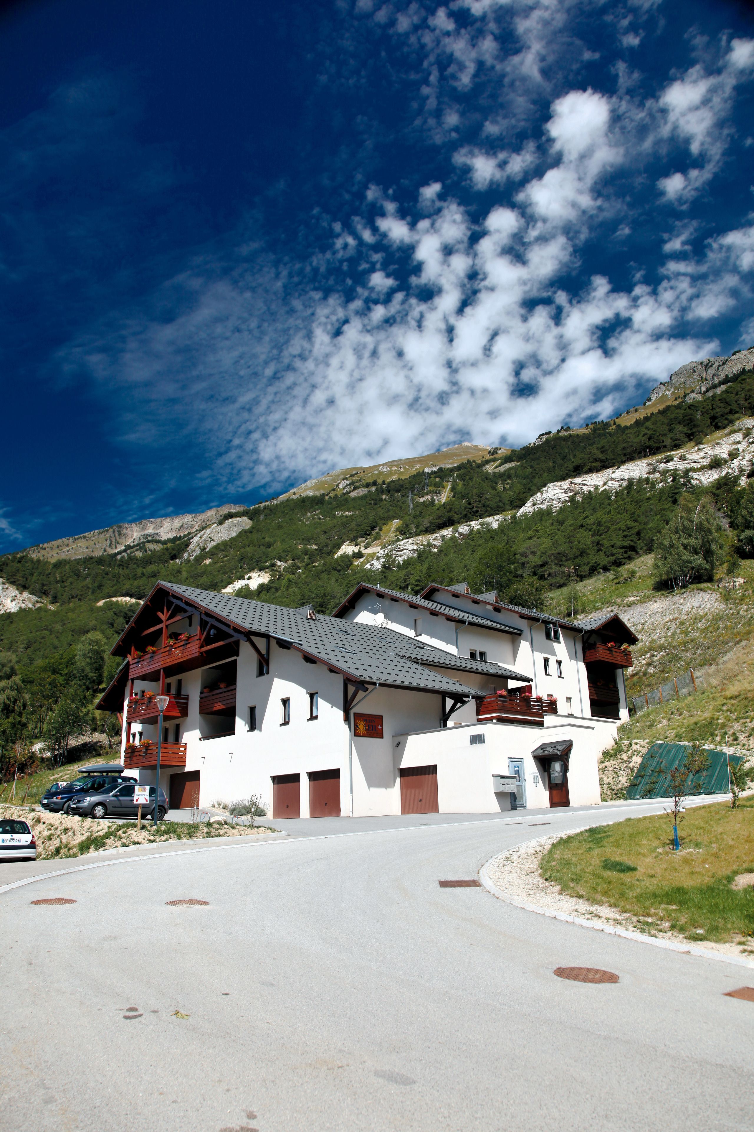 A white building with a sloped roof, multiple balconies, and a garage.