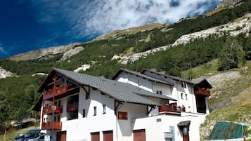 A white building with a sloped roof, multiple balconies, and a garage.