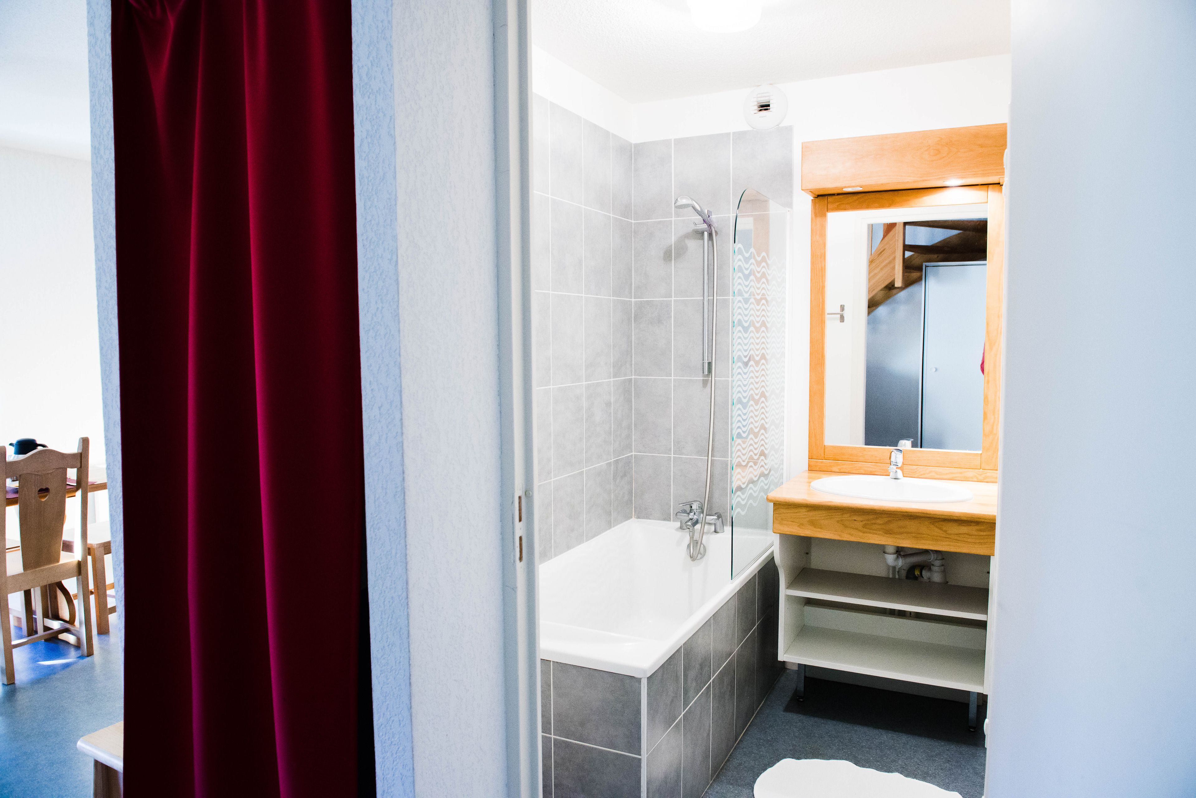 Un bagno moderno con una vasca, una doccia e un mobile bagno in legno con uno specchio.