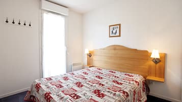 Une chambre à coucher avec une tête de lit en bois, une couvre-lit matelassée, deux lampes de chevet, un tableau au mur et une fenêtre avec un rideau.