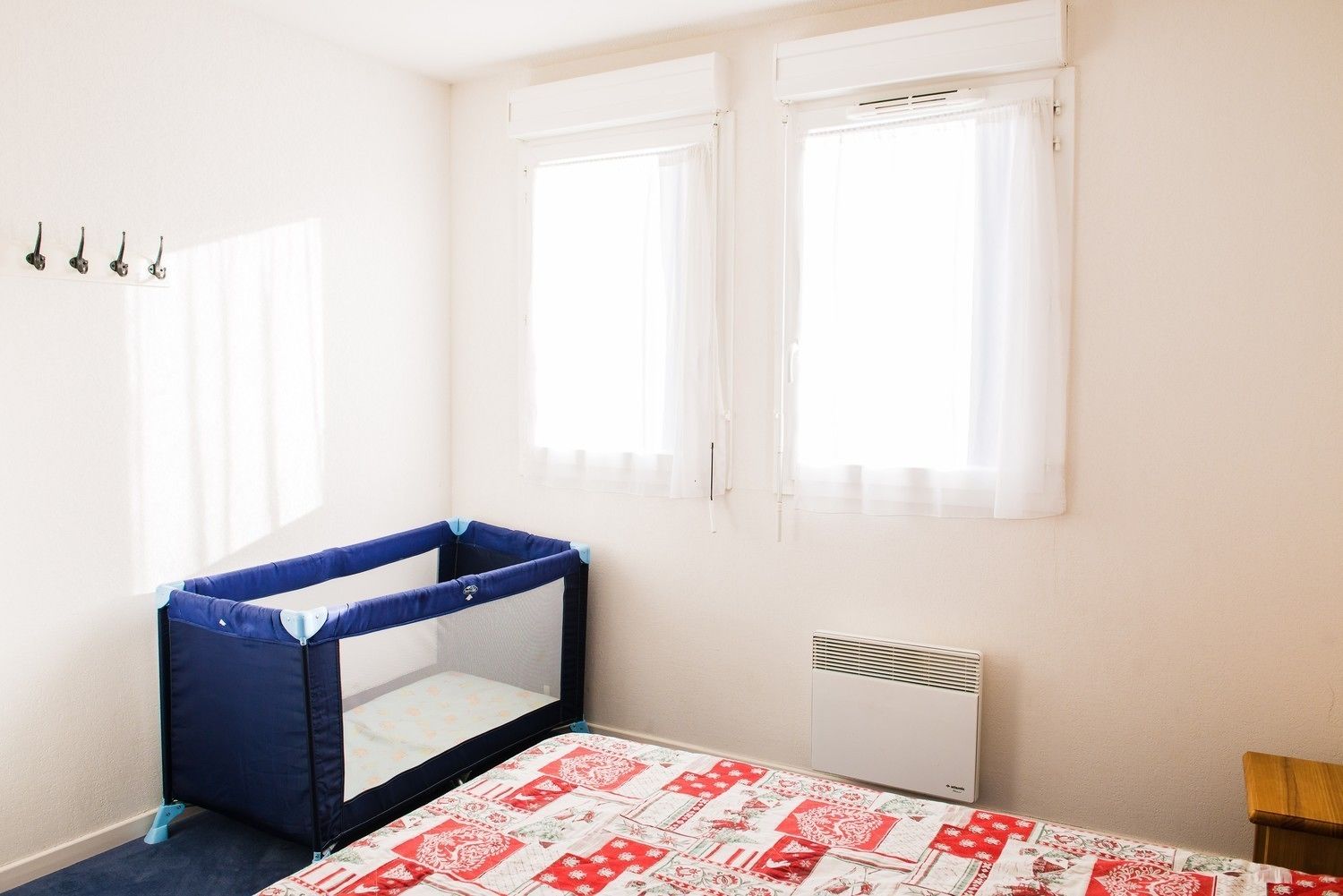 A room with a crib, a radiator, and a window with curtains.