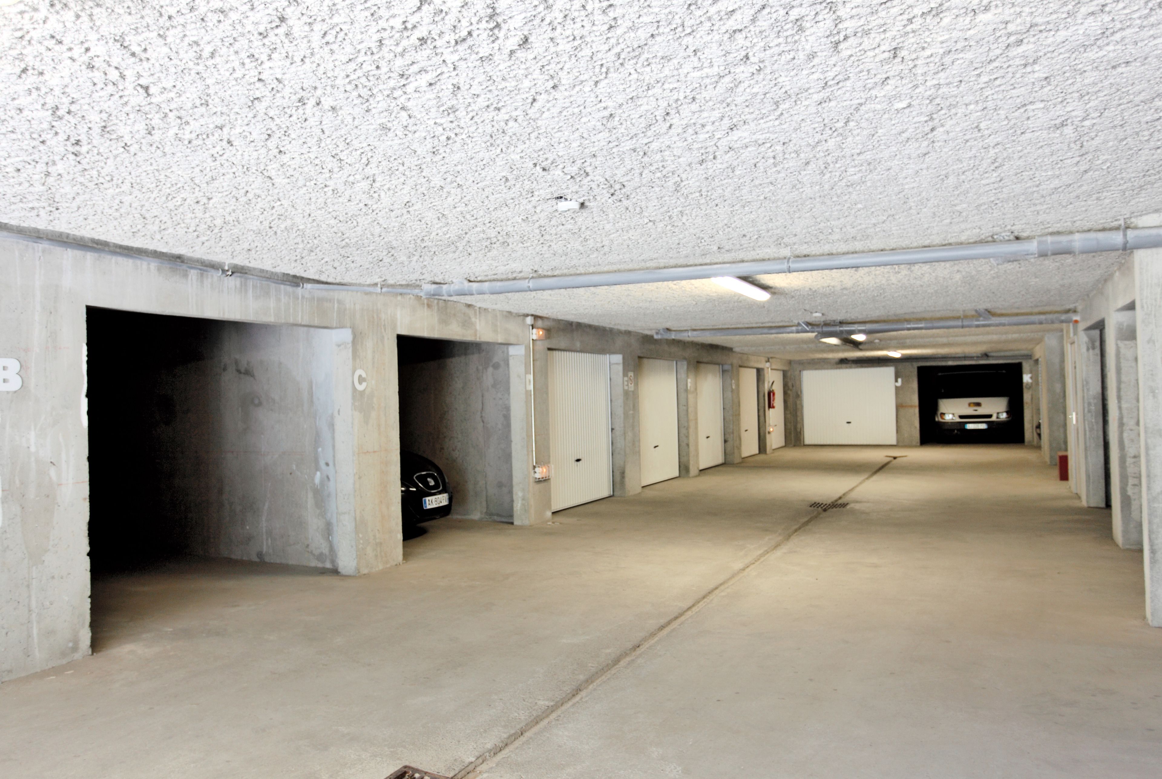 Eine lange, leere Tiefgarage mit Betonwänden und ebener Decke.