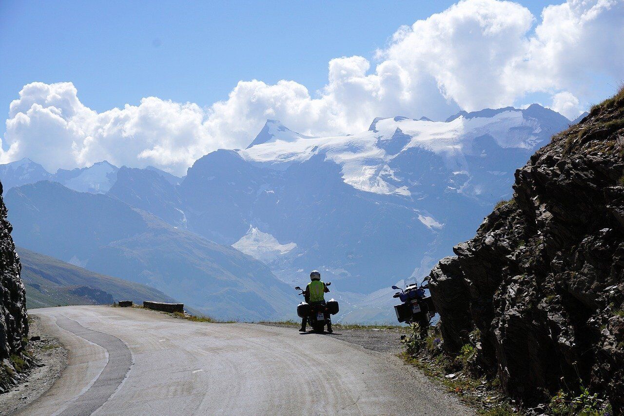 A winding mountain road with a motorcyclist in the distance.