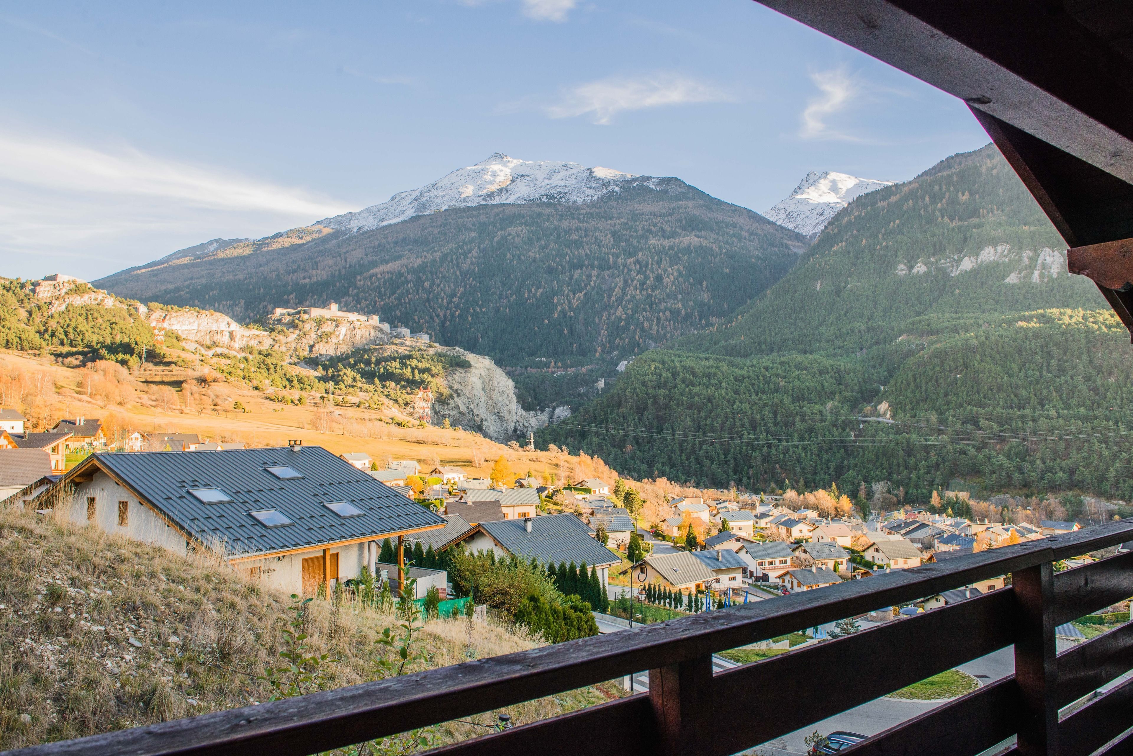 A mountain village with houses and a snow-capped peak in the background.
