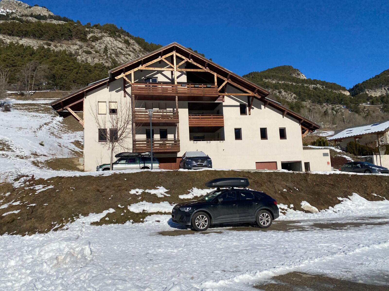 Un chalet de dos plantas con fachada de madera, un balcón y un porche cubierto.