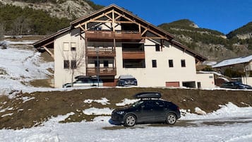 Un chalet de dos plantas con fachada de madera, un balcón y un porche cubierto.