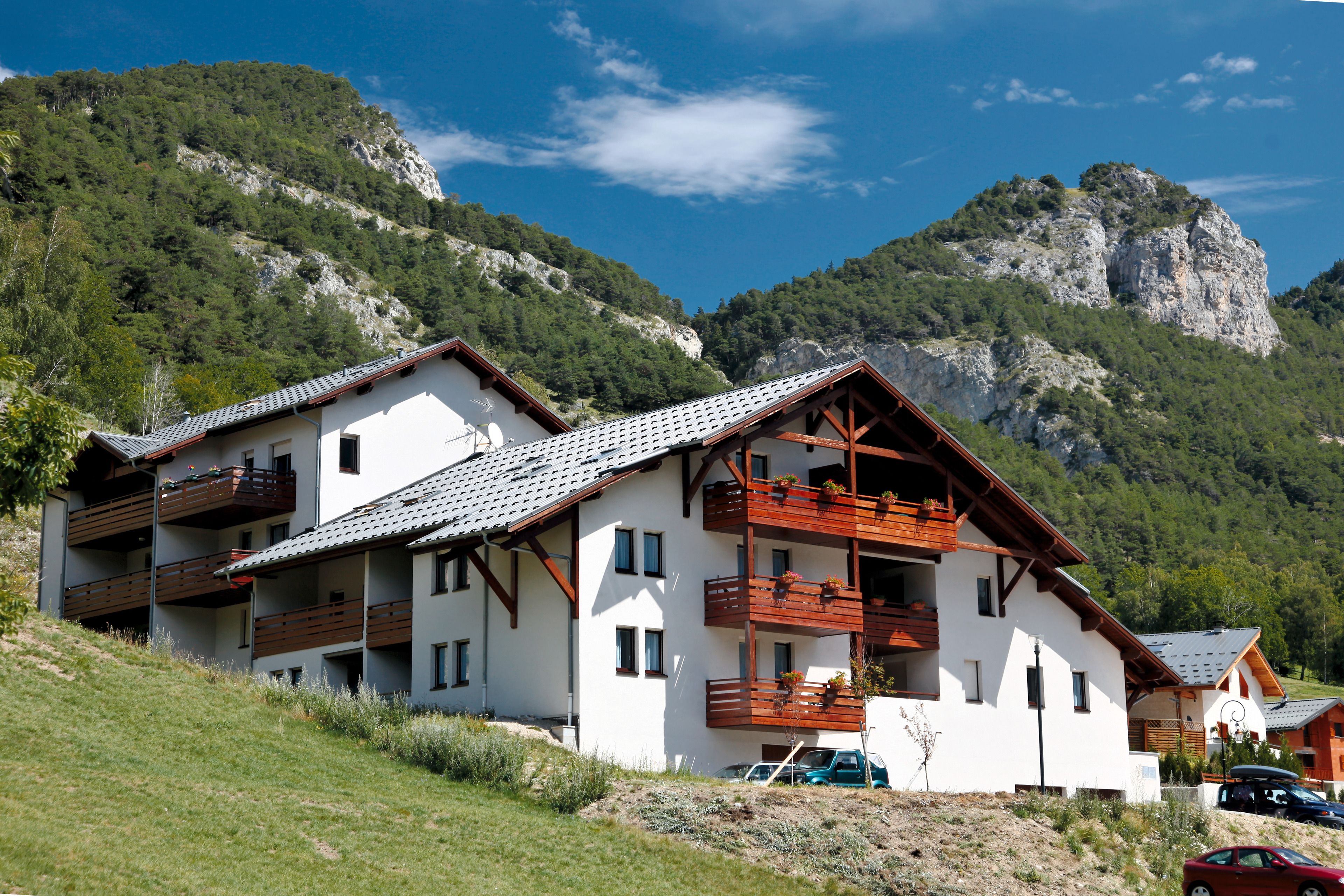 A modern building with multiple balconies, surrounded by a mountainous landscape.