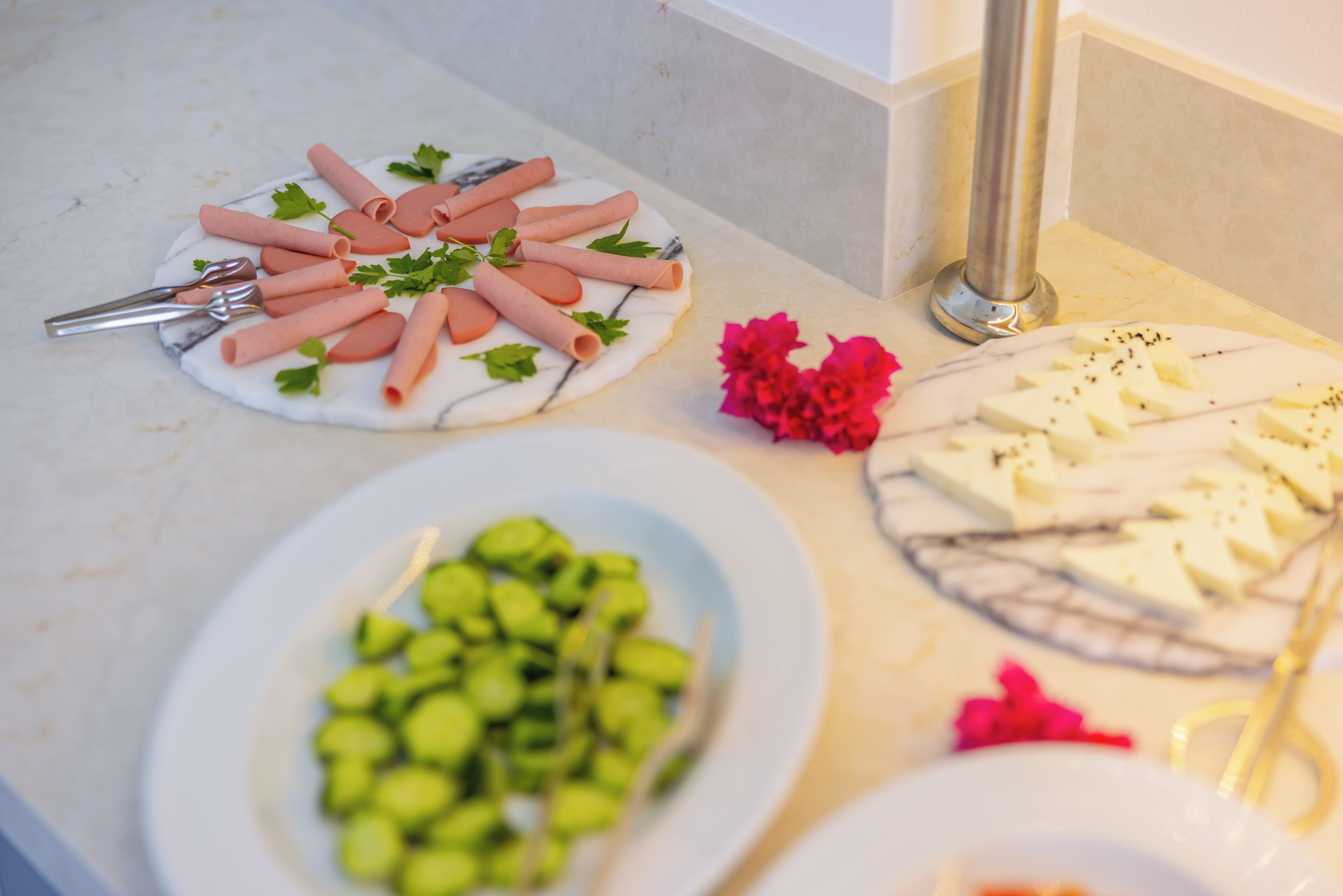 Una mesa de buffet con diversos alimentos, como embutidos, queso y verduras.