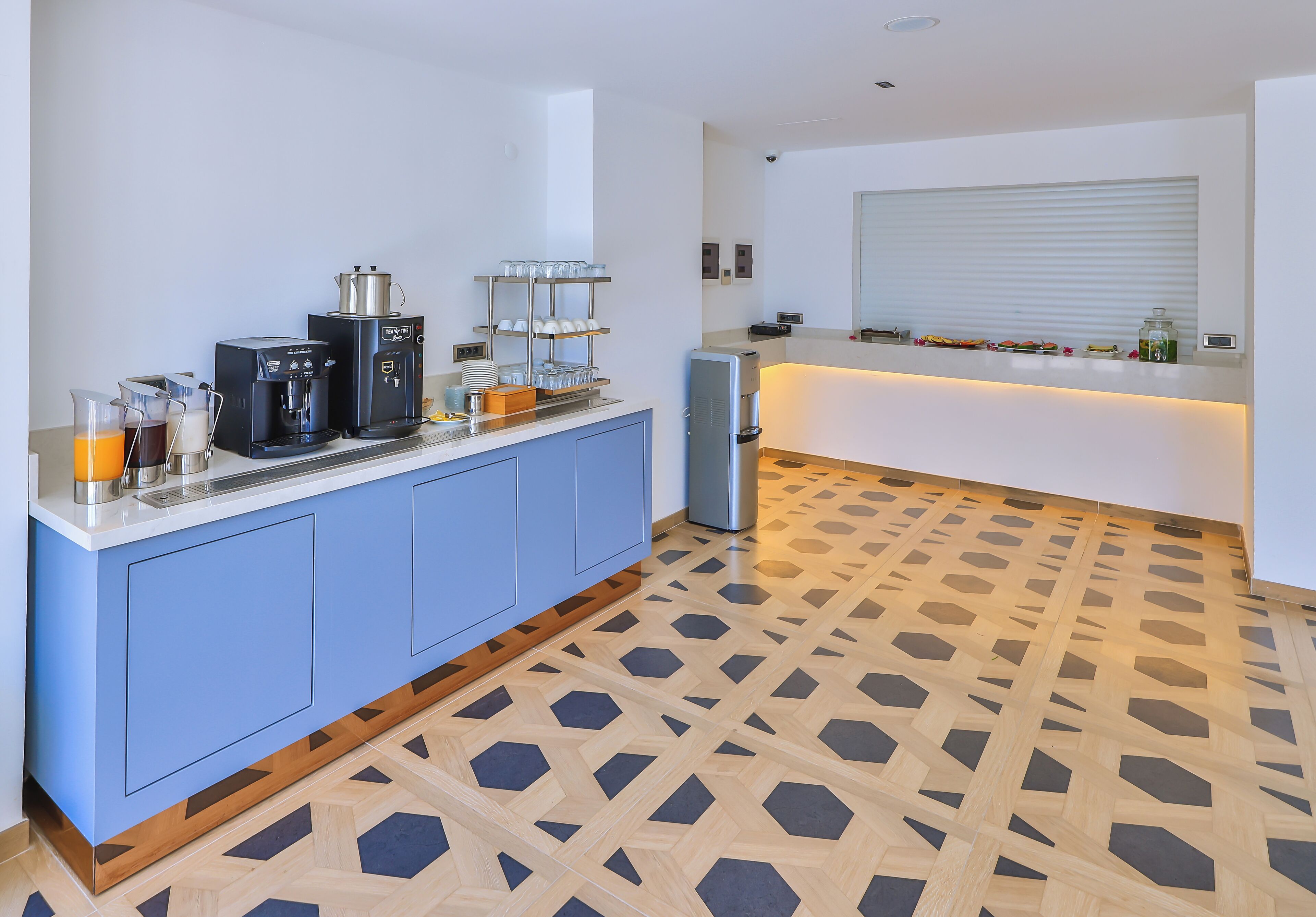 A modern kitchen with a coffee station, a refrigerator, and a breakfast bar.
