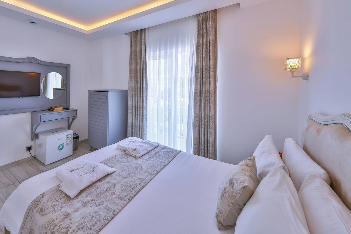 A neatly arranged hotel room with a bed, a desk, a television, and a wardrobe.