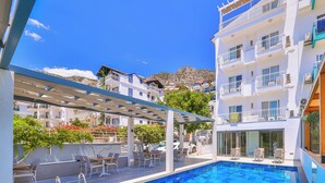 A swimming pool with a tiled deck, outdoor seating, and a view of surrounding buildings. - Linda Beach Class Hotel - Boutique Class (Kas)