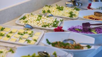 A buffet with various dishes, including cheese, vegetables, and garnishes.