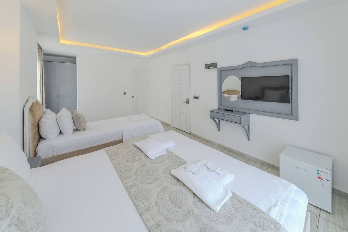 A hotel room with two beds, a TV, a mirror, and a bedside table.