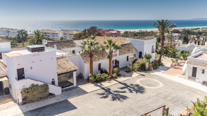 A coastal residential area with white buildings, palm trees, and a clear view of the beach and ocean. - Hotel El Cortijo De Zahara by Q Hotels (Tarifa)