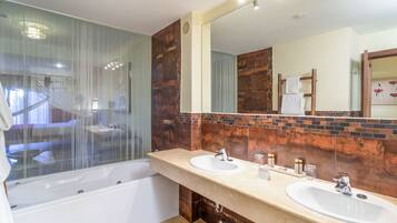 Un baño moderno con ducha de vidrio, dos lavamanos y un espejo grande.