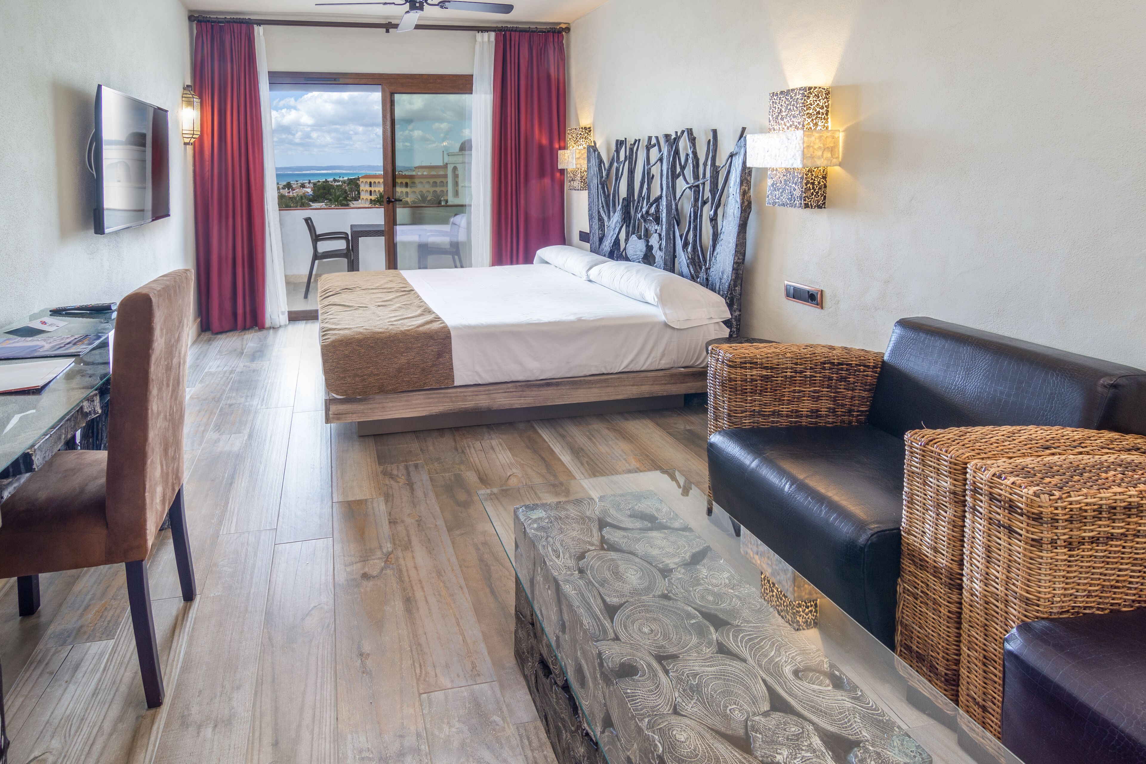 A hotel room with a bed, a desk, a chair, a sofa, and a view of the outdoors.