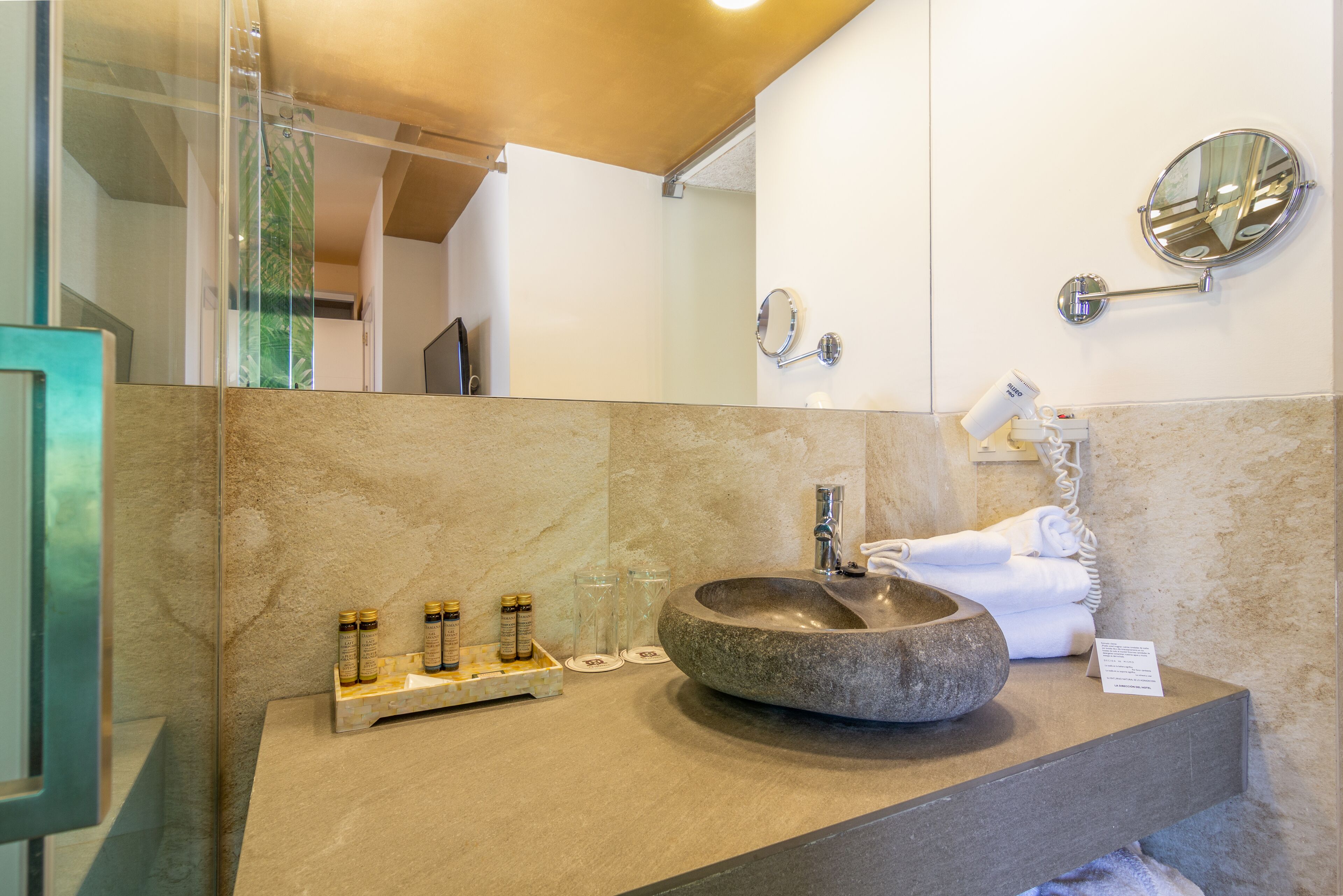 Un baño con un lavamanos de piedra, un espejo y artículos de tocador en la encimera.