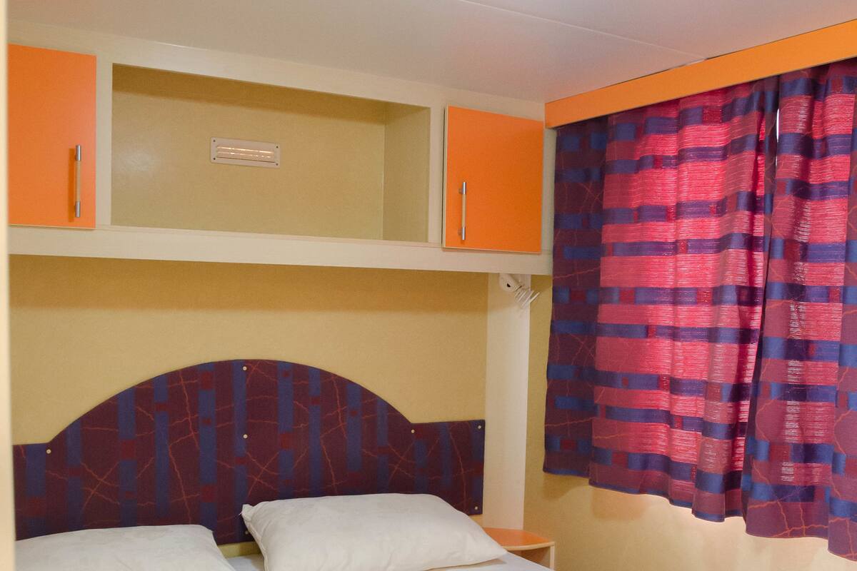 A single bed with a headboard, a bedside table, and a ceiling light fixture.
