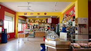 A brightly colored food market with various food stalls and a Coca-Cola refrigerator.