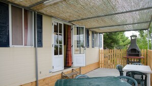 A covered patio area with a table and chairs, a wooden fence, and a barbecue grill.