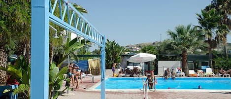 Una piscina al aire libre, cabañas de piscina (de pago), tumbonas