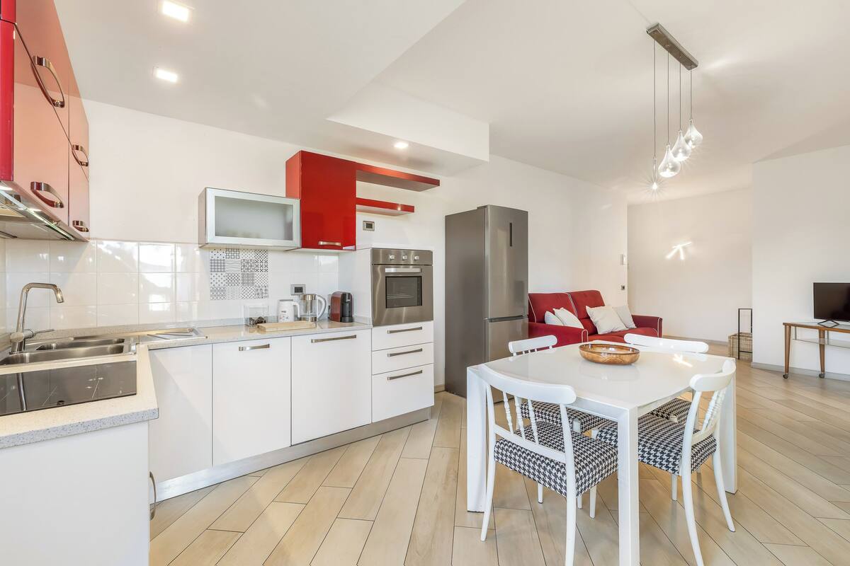 A modern kitchen with white cabinets, a stainless steel refrigerator, and a microwave.