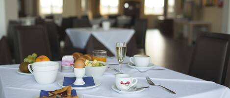 A dining table set with breakfast items including eggs, toast, fruit, and coffee.