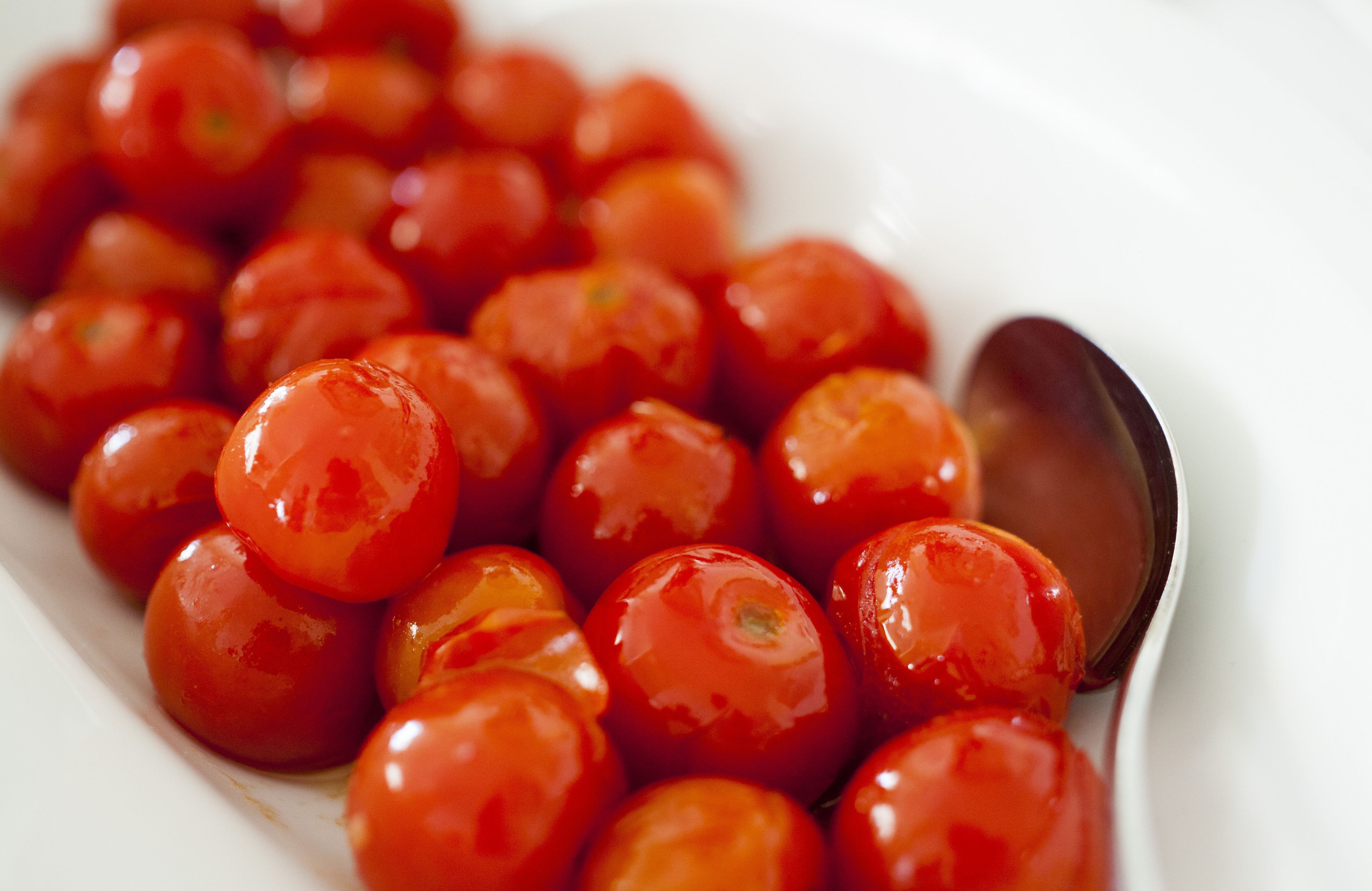 A white plate with glossy red cherry tomatoes.